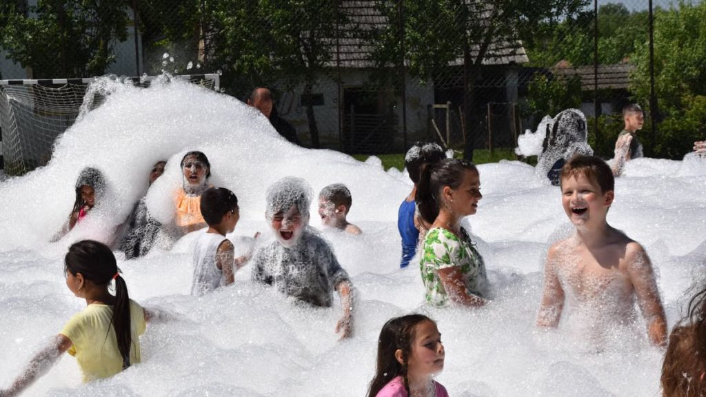 Children having fun in a foam party outdoors during summer.